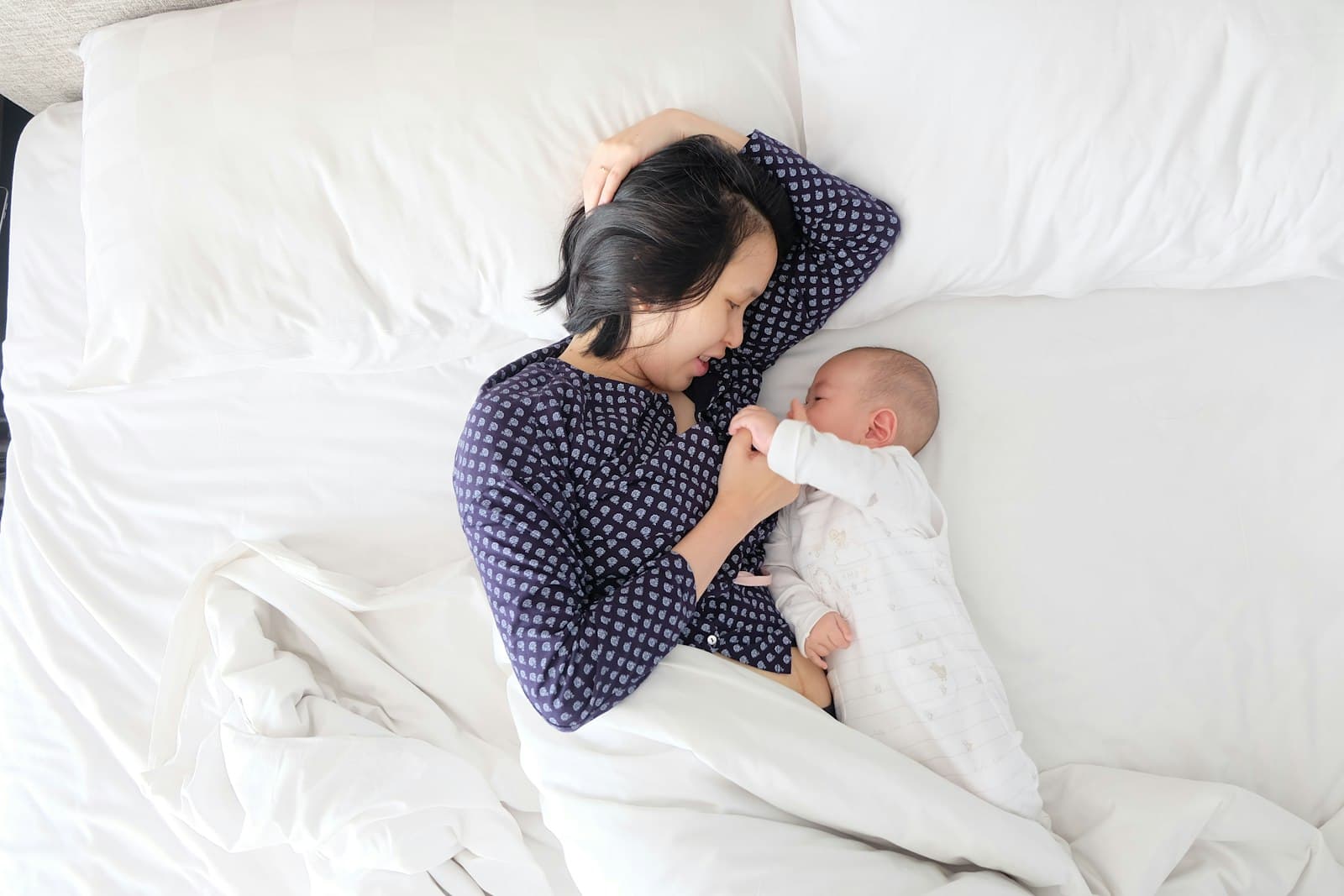 Parent lying in bed, holding newborn baby close after birth
